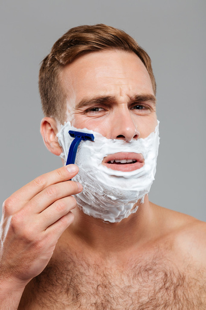 Man scares to shave over gray background - Foto, Imagem