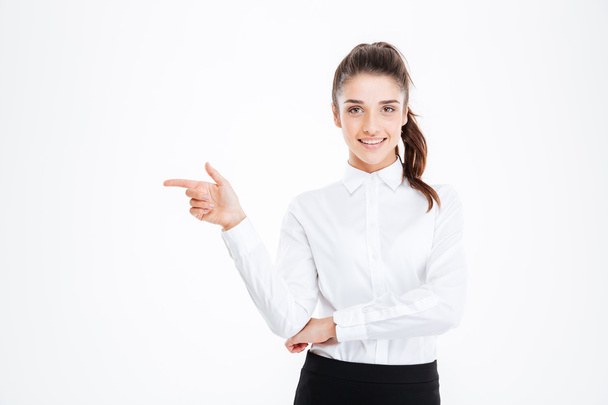 Portrait of a smiling young businesswoman pointing finger away - Photo, Image