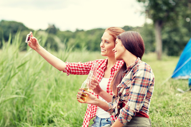 happy women taking selfie by smartphone at camping - 写真・画像