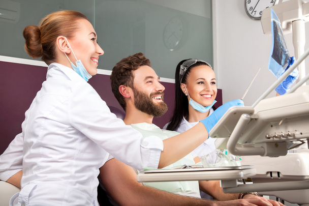 tandarts toont een patiënt x-ray van tanden - Foto, afbeelding