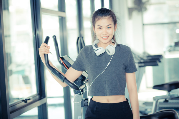 Dziewczyna Sport ze słuchawkami relaksujący na siłowni, ćwiczenia pracy - Zdjęcie, obraz
