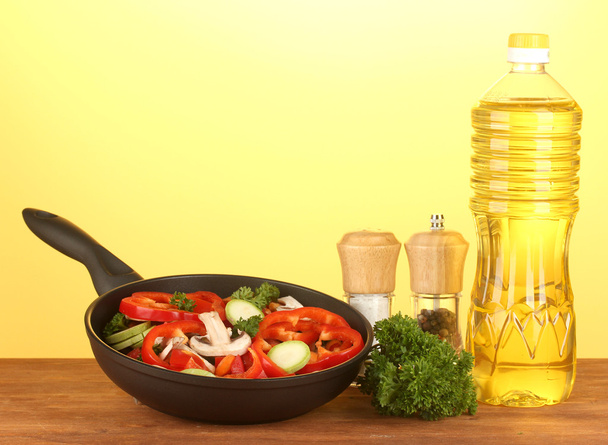 Frying pan with vegetables on yellow background - Photo, Image