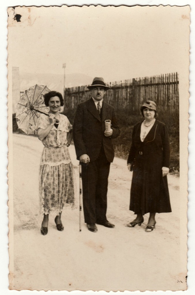  Foto vintage mostra mulheres e homens no resort spa. Uma das mulheres tem um guarda-sol. Fotografia original retro preto & branco
. - Foto, Imagem