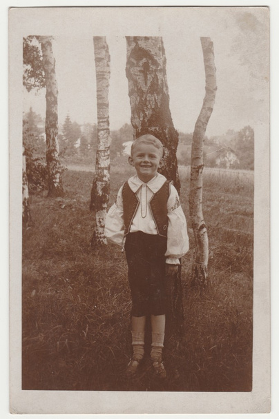 Ein altes Foto zeigt einen kleinen Jungen draußen. Im Hintergrund sind silberne Birken zu sehen. Retro Schwarz-Weiß-Fotografie. - Foto, Bild