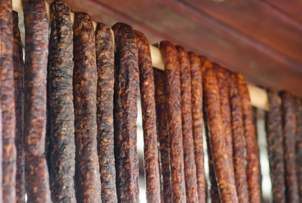 Salsichas tradicionais romenas penduradas em um pau de madeira
  - Foto, Imagem