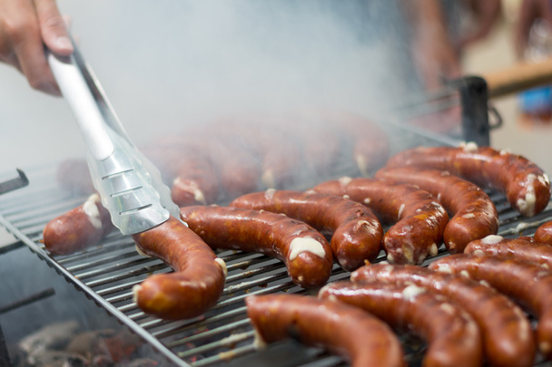 With tongs sausages are turned on grill - Photo, Image