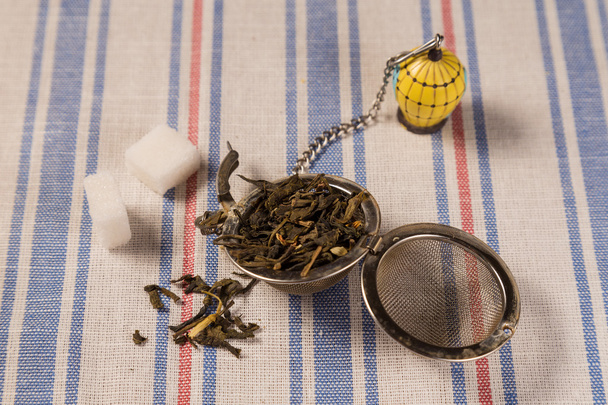 Colador de té con hojas secas de té verde
 - Foto, Imagen