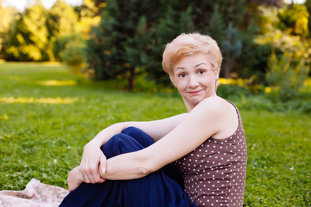Portrait of middle aged woman smiling in the park - Photo, Image
