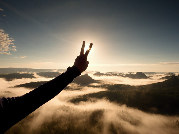 Die Hand des Menschen macht der Sonne den Sieg. nebliger Tagesanbruch in den Bergen - Foto, Bild