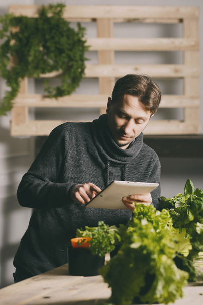 Man using his tablet while growing plants - Photo, image