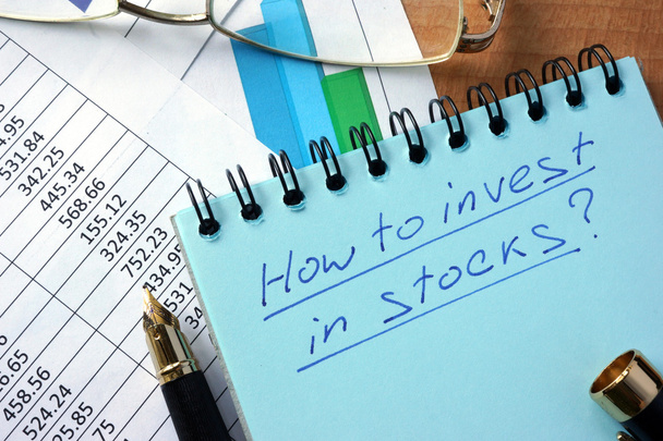 Notepad with inscription  how to invest in stocks on a table. - 写真・画像