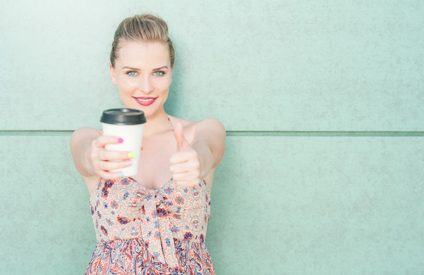 Chica mostrando taza de café y haciendo como gesto
 - Foto, imagen