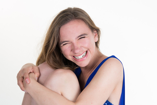 Směje se žena dlouhé vlasy bílé pozadí modré šaty sedí křeslo - Fotografie, Obrázek