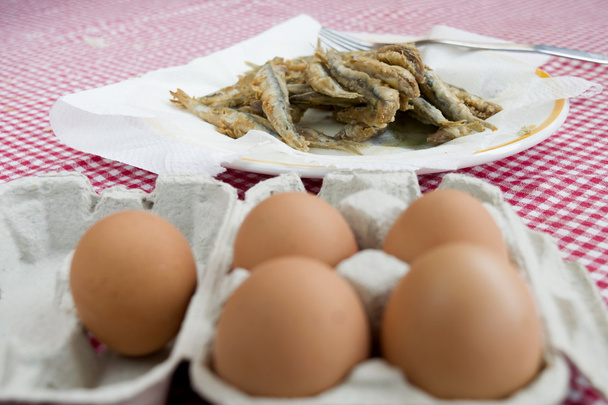 gebakken ansjovis met in de voorgrond verse eieren - Foto, afbeelding