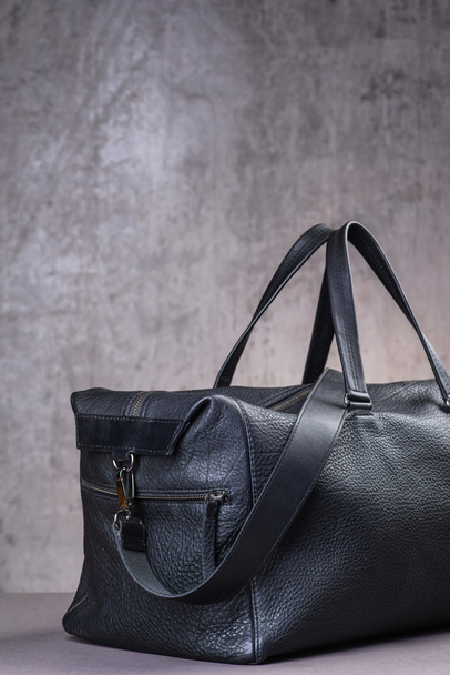 Black leather traveling bag, over the concrete wall background - Photo, Image