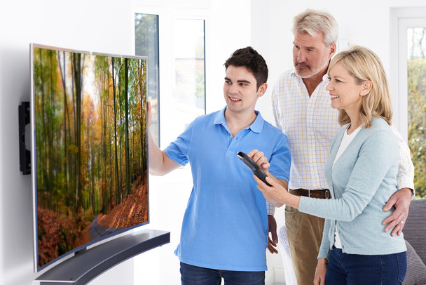 Мужчина демонстрирует новое телевидение пожилой паре дома
 - Фото, изображение