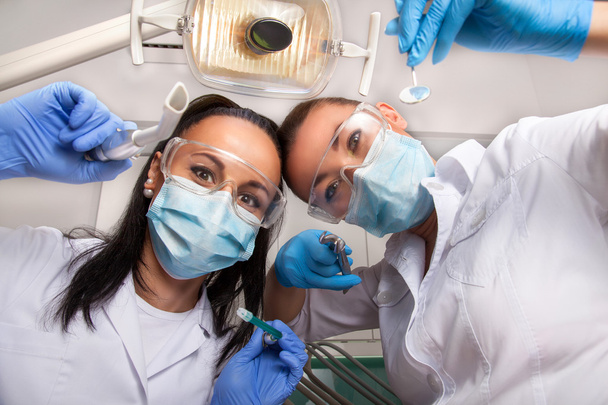 Kobieta lekarz dentysta i asystent w maskach patrząc na kamery - Zdjęcie, obraz