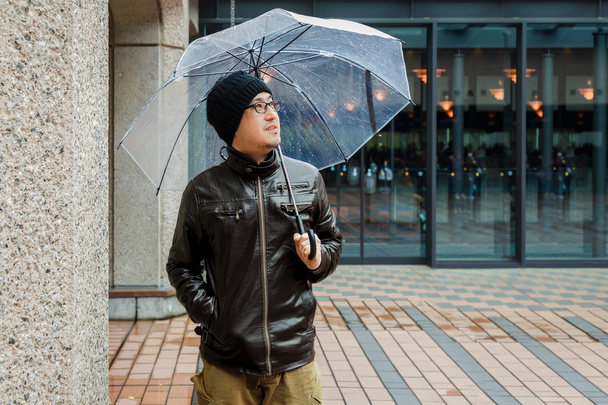 Egy ázsiai ember a barna kabátot, világos esernyő - Fotó, kép