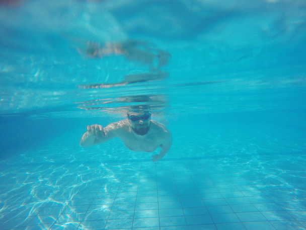 Γενειάδα άνδρας με γυαλιά βουτιές κάτω από το νερό της πισίνας - Φωτογραφία, εικόνα