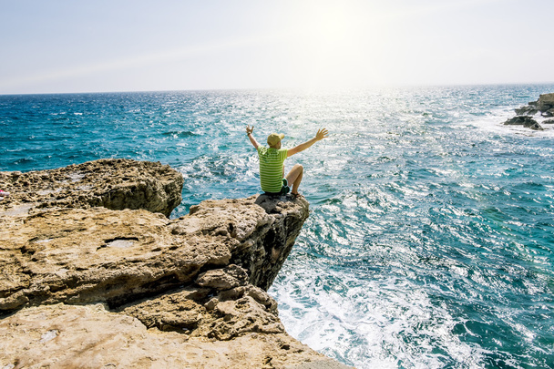 A man sits on a ledge of rock above the sea at Cape Greco . Cypr - Foto, Imagem