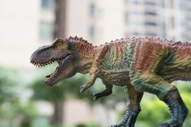 закрыть голову тираннозавра игрушки со зданием на заднем плане
 - Фото, изображение