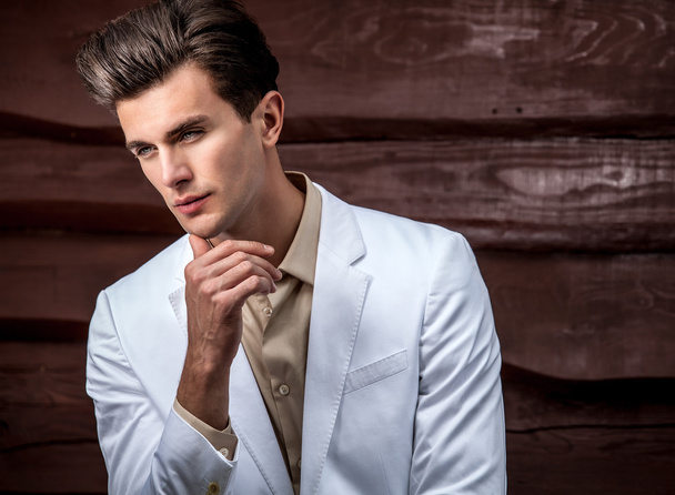 Portrait of young beautiful fashionable man against wooden wall - 写真・画像