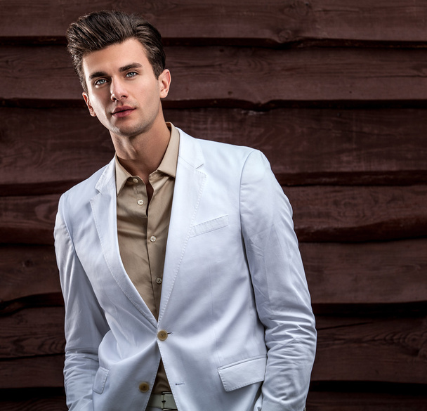 Portrait of young beautiful fashionable man against wooden wall - Photo, Image