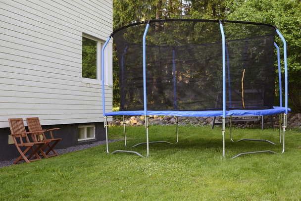 trampoline sur la pelouse à côté de la maison
 - Photo, image