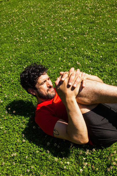 Αστική αθλητής που κάνει το τέντωμα ασκεί στο γρασίδι - Φωτογραφία, εικόνα