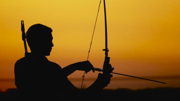 Archery silhouette, sun sets behind the archer. Young hunter. - Footage, Video