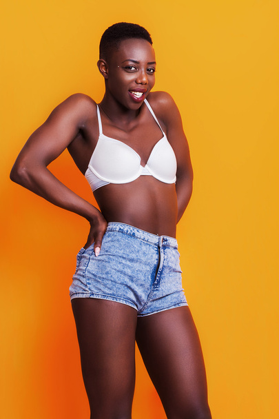 Портрет счастливой африканской девушки в джинсовых шортах и лифчике
 - Фото, изображение
