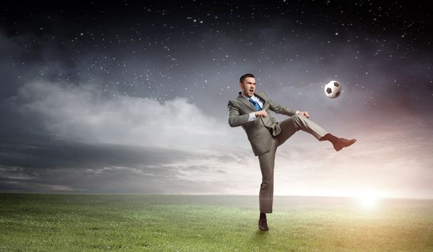 ビジネスマンの蹴るボール。ミクスト メディア - 写真・画像