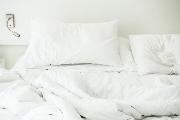 Rumpeliges Bett mit weißem, unordentlichem Kissen  - Foto, Bild