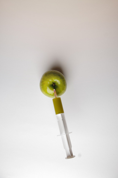 Manzana transgénica con jeringa en blanco
 - Foto, imagen