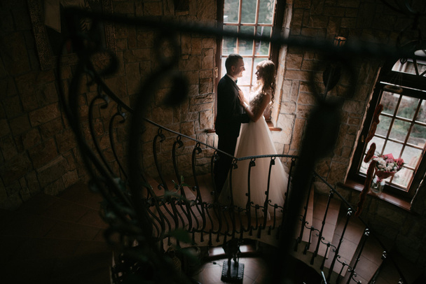 Young married couple standing face-to-face at the stairs and holding hands - Foto, Imagem