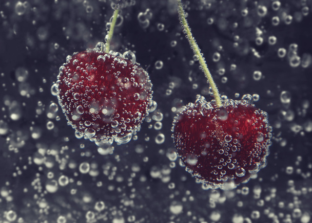 świeżych wiśni w czystej wodzie z bąbelkami z bliska na ciemnym tle - Zdjęcie, obraz