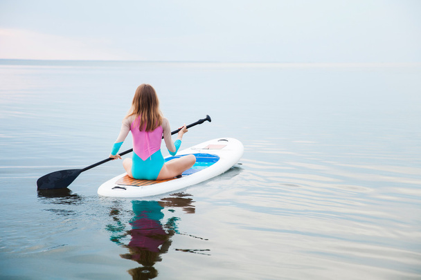 Unrecognizable young woman paddling on sup board - Foto, immagini
