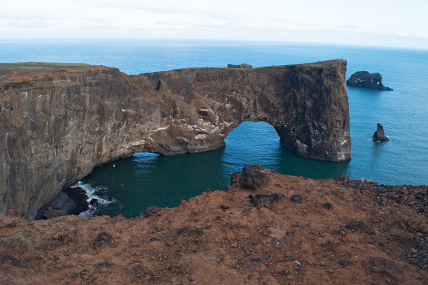 Islândia, Europa: vista aérea do gigantesco arco negro de lava em pé no mar no promontório de Dyrholaey e com vista para a baía de Vik i Myrdal, a aldeia mais ao sul da ilha, uma das principais atrações turísticas do sul
 - Foto, Imagem