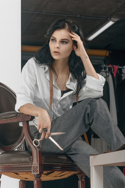 Fashion designer sitting with scissors in her hand. - Valokuva, kuva