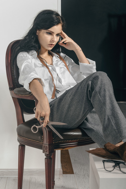 Fashion designer sitting with scissors in her hand. - Zdjęcie, obraz