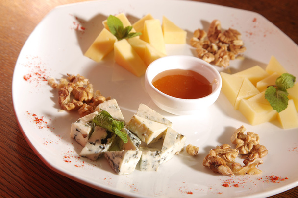 different cheeses on a plate with walnuts and honey on plate - Photo, image