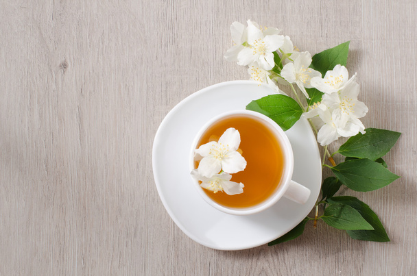 Widok z góry z kubkiem herbaty ziołowe i kwiaty jaśminu na drewnianym stole, miejsca na tekst - Zdjęcie, obraz
