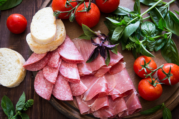 Antipasto met bresaola, ham en salami. brood, tomaat en basilicum - Foto, afbeelding
