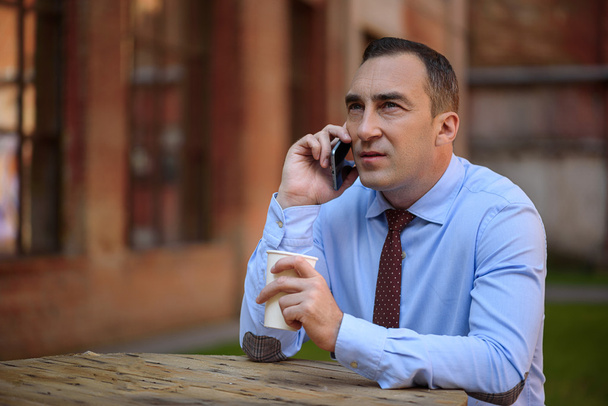Confident businessman talking on telephone outdoors - Zdjęcie, obraz