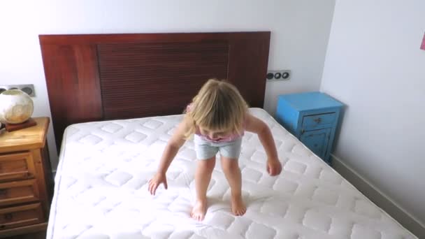 blonďaté dítě skákání na matrace doma zpomalené - Záběry, video