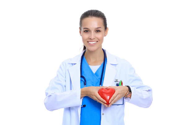 Positive female doctor standing with stethoscope and red heart symbol isolated - Foto, immagini