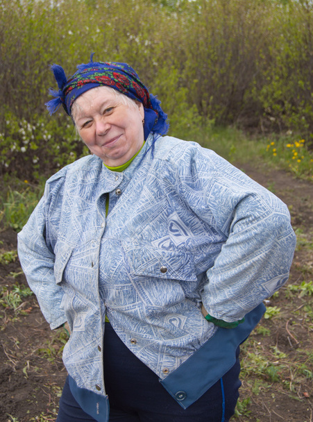 Χαμογελώντας ηλικιωμένη γυναίκα σε ένα μαντήλι στον κήπο σας - Φωτογραφία, εικόνα