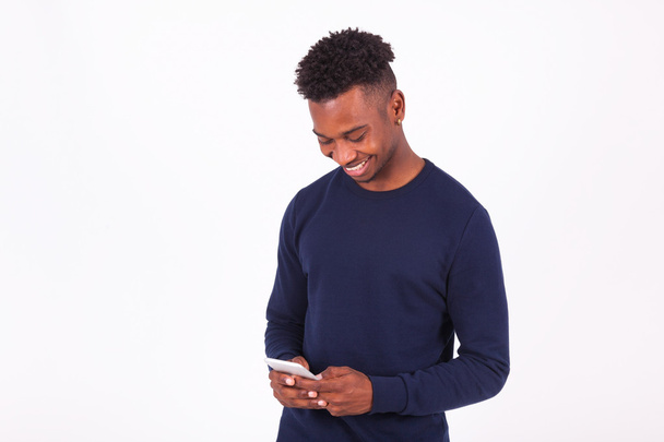 Young African American man sending a sms text message on his sma - Photo, Image