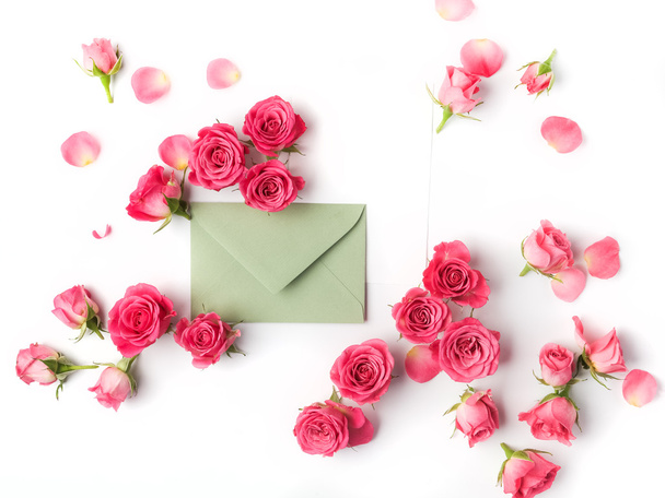 Envelop with white card and rose background. Flat lay, top view. - Fotó, kép