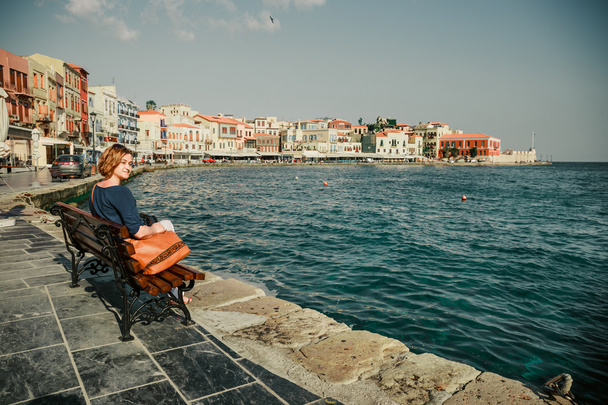 ベンチに座って、チャニア、クレタ島、ギリシャの旧港を見て若い女性 - 写真・画像